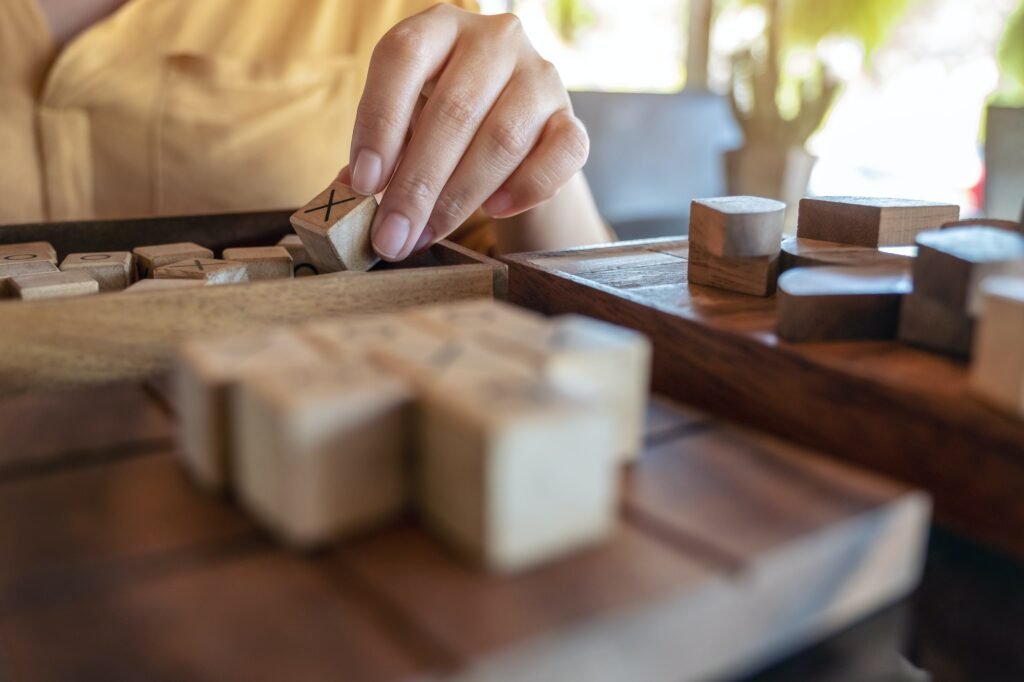 Closeup image of people playing wooden Tic Tac Toe game or OX game